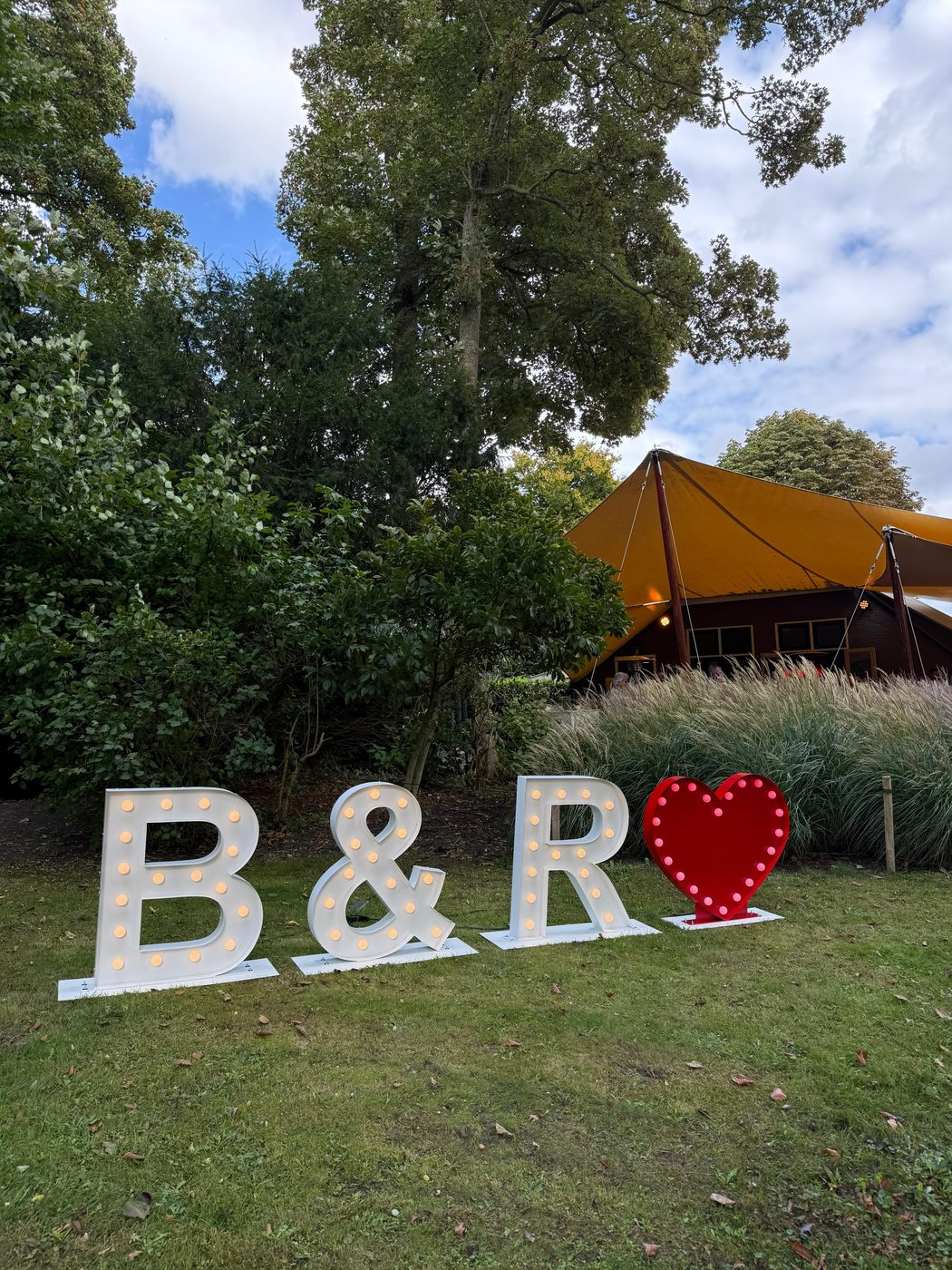 B en R lichtletters met verlicht rood hart op een bruiloft buiten