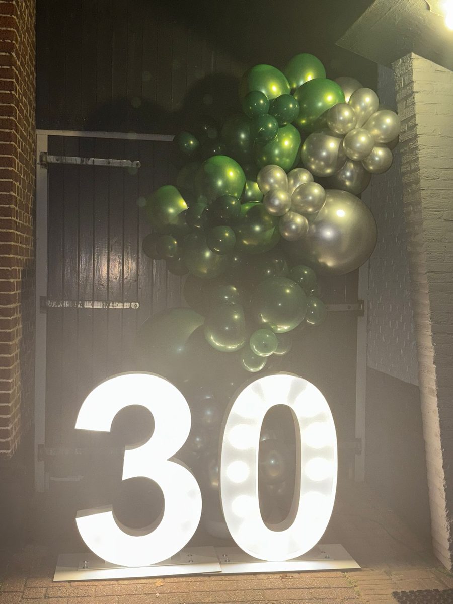 Verlichte lichtcijfers 30 met groene en zilveren ballonnen buiten in de avond