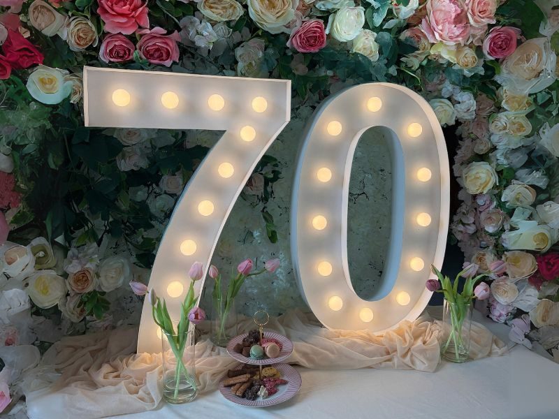 Verlichte lichtcijfers 70 voor een bloemenwand bij een jubileum in Hoogeveen