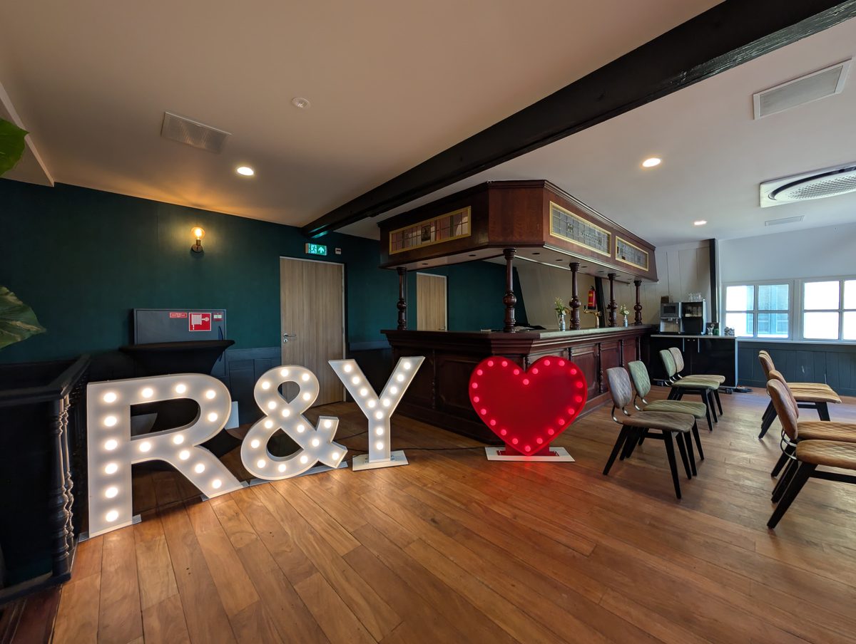 R en Y lichtletters met rood hart op een bruiloft in een sfeervolle zaal