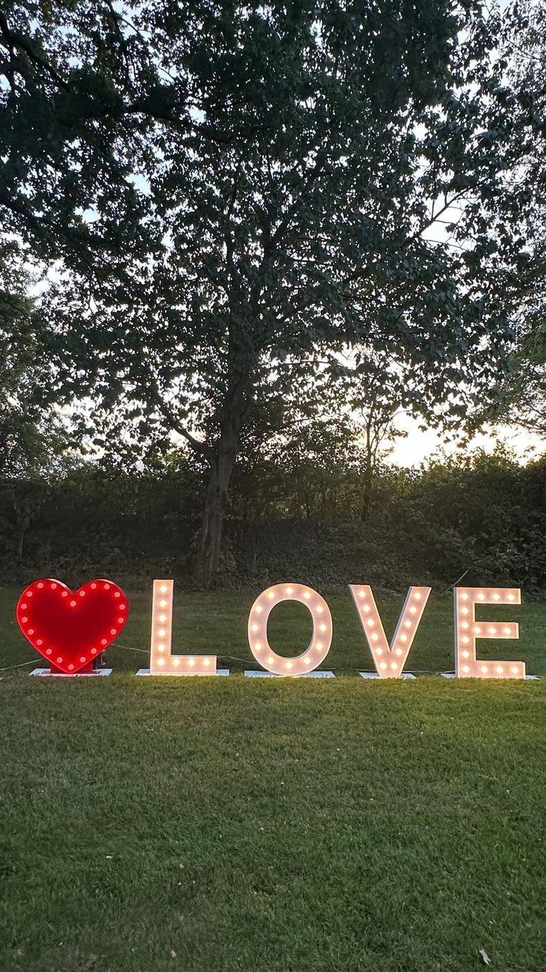 LOVE lichtletters met rood hart op een grasveld bij zonsondergang